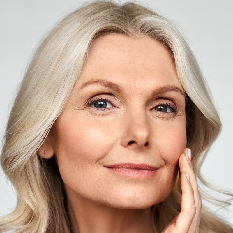 Beautiful gorgeous 50s mid aged mature woman looking at camera isolated on white. Mature old lady close up portrait. Healthy face skin care beauty, middle age skincare cosmetics, cosmetology concept